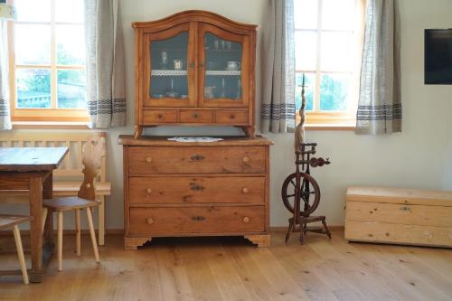 a wooden dresser in a room with a table and window at Bauernhof Gschmeidler in Sankt Johann im Saggautal