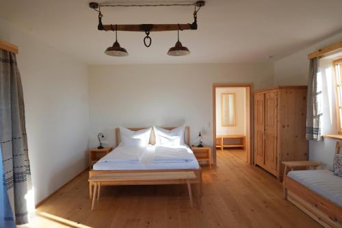 a bedroom with a bed with white sheets and wooden floors at Bauernhof Gschmeidler in Sankt Johann im Saggautal