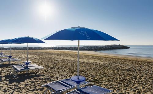 two blue umbrellas and lounge chairs on a beach at Hapimag Apartments Cavallino in Cavallino-Treporti