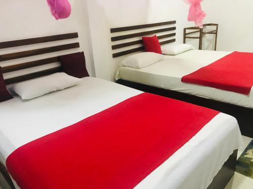 two beds in a room with red and white sheets at Geethani Tourist Home Polonnaruwa in Polonnaruwa