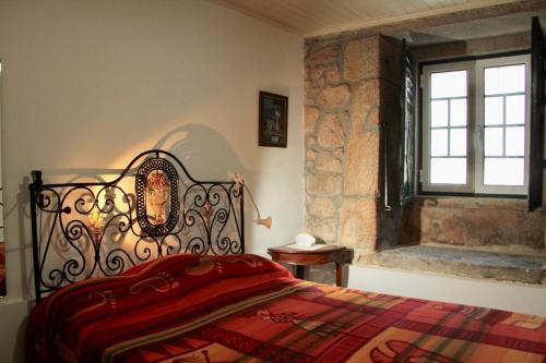 a bedroom with a bed with a red blanket and a window at Casa do Balcão in Alcains
