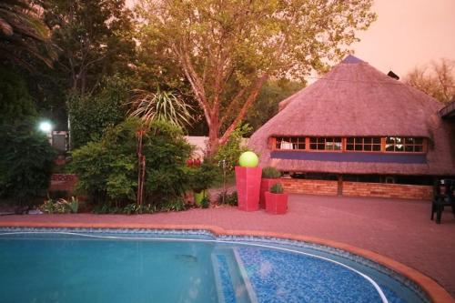 a hut with a swimming pool in front of a house at Chic Breeze in Bloemfontein