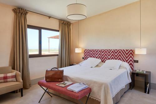 a bedroom with a large bed and a chair at Trafalgar Polo Club in El Palmar
