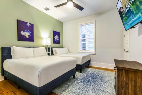 um quarto com 2 camas e uma televisão de ecrã plano em Hosteeva Private Condo w Pool and High-end amenities Near Frnch Quarter em Nova Orleans