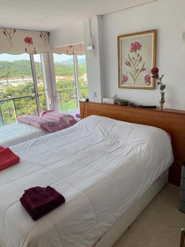 a bedroom with a large white bed and a window at Apartamento en primera línea de mar, 8 personas in Platja d'Aro