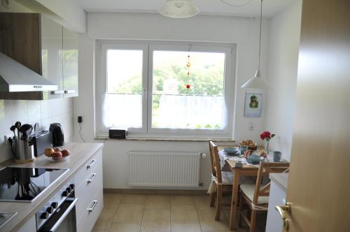 a white kitchen with a table and a window at Rothaarsteig Ferienhaus in Kirchhundem