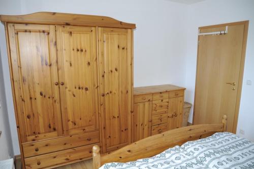 a bedroom with a wooden cabinet and a bed at Rothaarsteig Ferienhaus in Kirchhundem