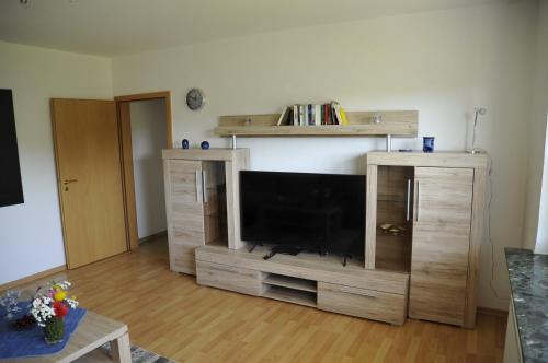 a living room with a flat screen tv in a wooden entertainment center at Rothaarsteig Ferienhaus in Kirchhundem
