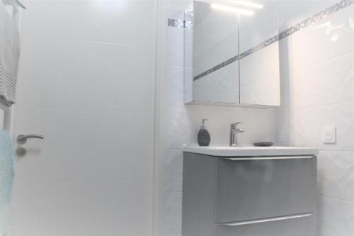 Baño blanco con lavabo y espejo en Appartement tout équipé, cosy (1 station de Paris) en Saint-Denis