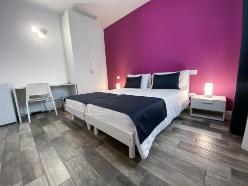 1 dormitorio con 1 cama grande y pared morada en Bonne Nuit Guest House en Azzano San Paolo