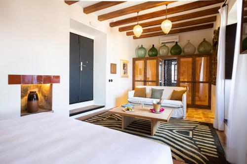 a bedroom with a bed and a couch and a table at Hotel La Torre del Canonigo - Small Luxury Hotels in Ibiza Town