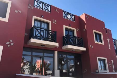 a red building with balconies on the side of it at APARTAMENTO MOCHIMA in Cotillo
