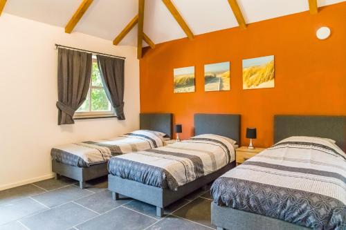 3 camas en una habitación con paredes de color naranja en Valkenhof Schimmert, en Schimmert