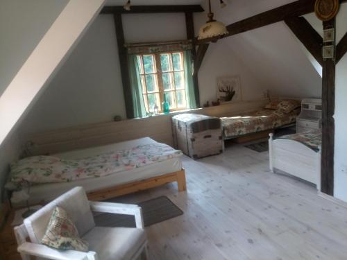 a attic room with two beds and a chair at Sielski Zakątek Tokary in Tokary