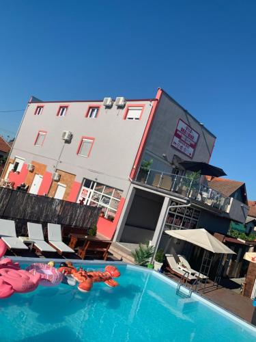 a hotel with a swimming pool in front of a building at Apartments Vila Brzi & Beka in Šabac