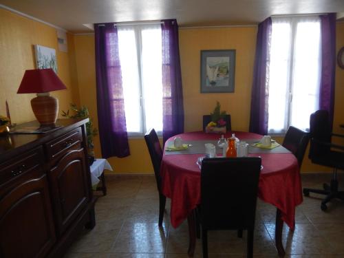 une salle à manger avec une table rouge avec des chaises et des fenêtres dans l'établissement Chez Corinne, à La Roche-Chalais