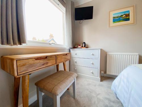 a bedroom with a desk and a bed and a window at Cairngorm Guest House in Aviemore