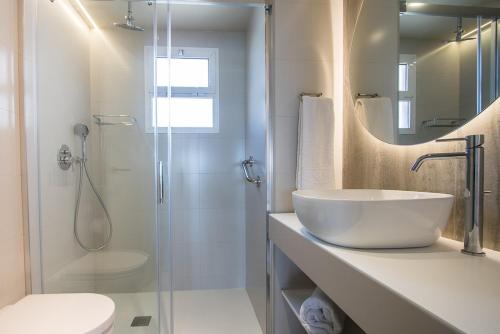 ein weißes Bad mit einem Waschbecken und einer Dusche in der Unterkunft Les Dunes Comodoro in Benidorm
