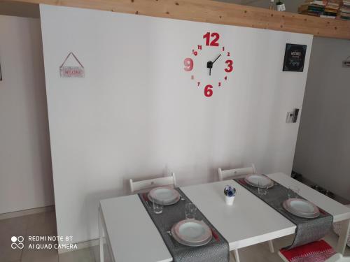 a dining room with a table and a clock on the wall at Chez Mémé in Lesina