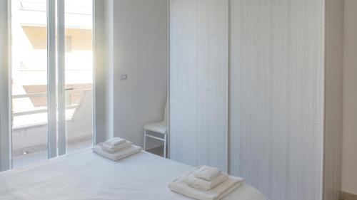 una camera da letto bianca con due asciugamani su un letto di Welcomely - La Maddalena 20 ad Alghero