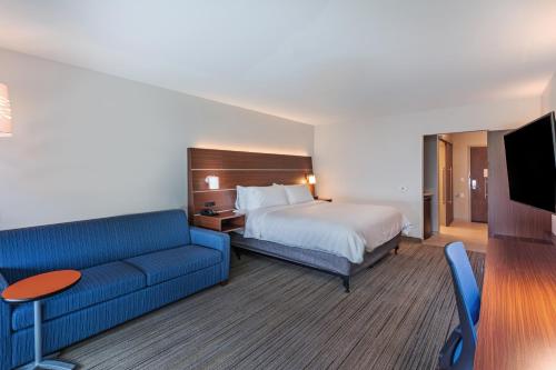 a hotel room with a bed and a blue couch at Holiday Inn Express & Suites - Parsons, an IHG Hotel in Parsons