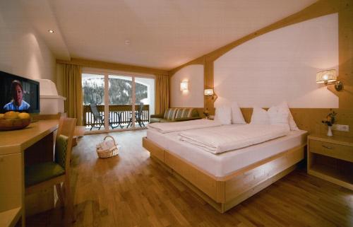Schlafzimmer mit einem Bett, einem Schreibtisch und einem TV in der Unterkunft Hotel Grones in St. Ulrich in Gröden