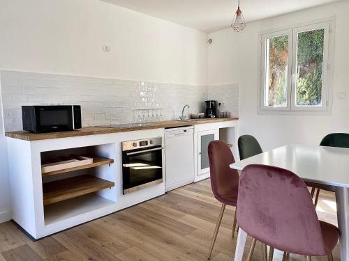 uma cozinha com uma mesa e cadeiras e um micro-ondas em Propriété Malva appartement agava em Alata