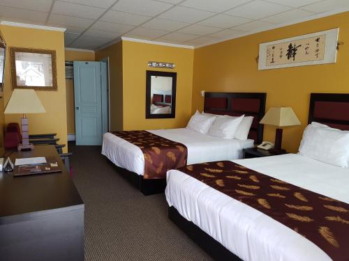two beds in a hotel room with yellow walls at Alpine Inn & Suites in Revelstoke