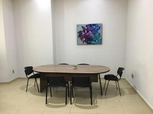 a dining room table with chairs and a painting on the wall at Hotel Casino Plaza in Guadalajara