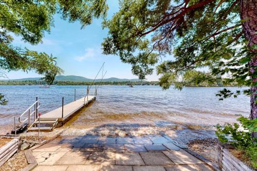 a dock on a lake with a boat in the water at Main House in Ossipee