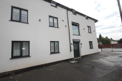 a white building with black windows and a door at Holden Court Apartment 5 in West Drayton