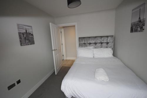 um quarto com uma cama grande e lençóis brancos em Holden Court Apartment 5 em West Drayton