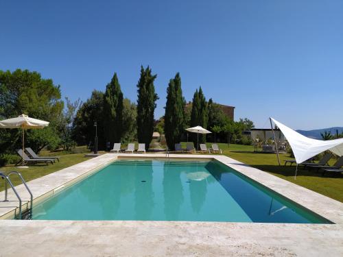 a swimming pool in a yard with chairs and umbrellas at Locanda Cugnanello in Anqua