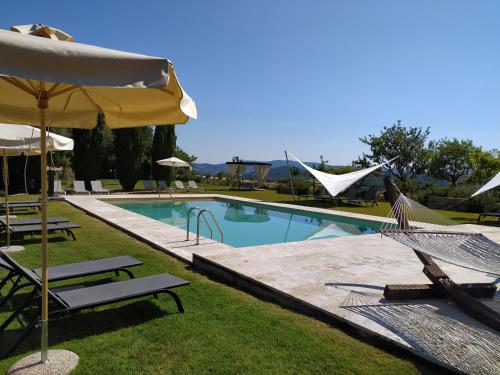 a swimming pool with two chairs and an umbrella at Locanda Cugnanello in Anqua