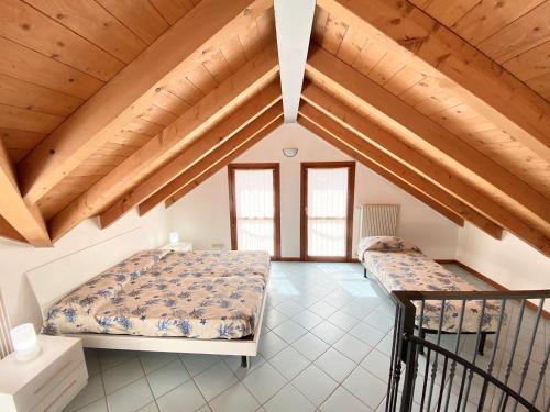 two beds in a room with wooden ceilings at Villa Santin Carraro Immobiliare - Family Apartments in Lido di Jesolo
