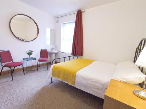 - une chambre d'hôtel avec un lit et un miroir dans l'établissement Carnation Flat A in Wembley, à Londres