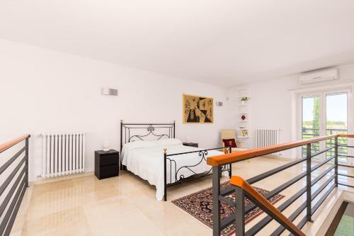 a white bedroom with a bed and a balcony at Tenuta Giardini Nuovi in Novoli