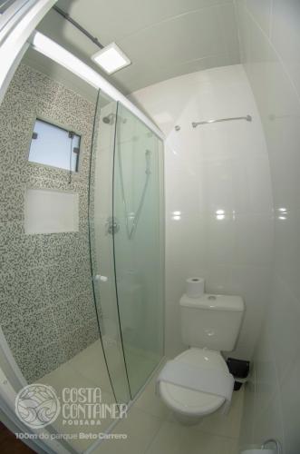 a bathroom with a toilet and a glass shower at Pousada Costa Container in Penha
