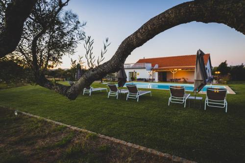 um grupo de cadeiras e guarda-sóis ao lado de uma piscina em Vila Fuzeta Bed & Breakfast em Fuzeta