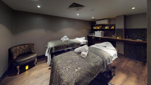 a treatment room with two beds and a chair at Holiday Inn London Kensington High St. by IHG in London