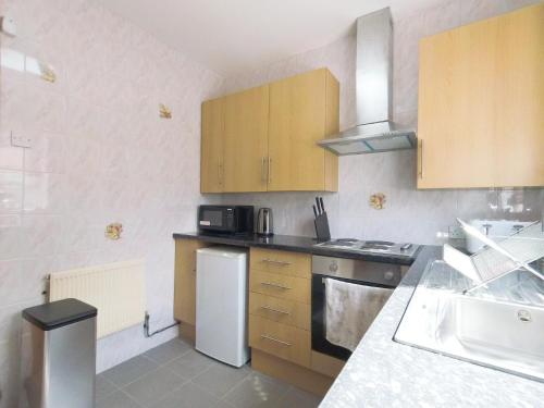a kitchen with wooden cabinets and a white refrigerator at Carnation Flat A in Wembley in London