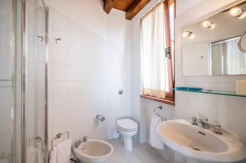 La salle de bains blanche est pourvue d'un lavabo et de toilettes. dans l'établissement Villa Limonaia, à Gargnano