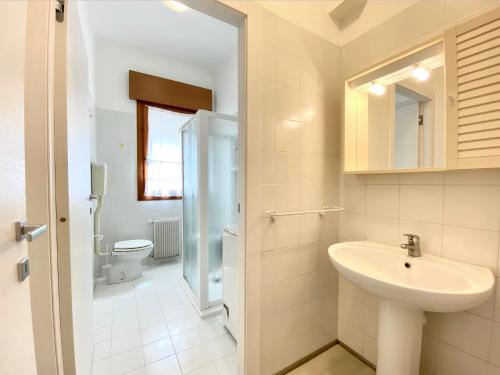a white bathroom with a sink and a toilet at Villa Santin Carraro Immobiliare - Family Apartments in Lido di Jesolo