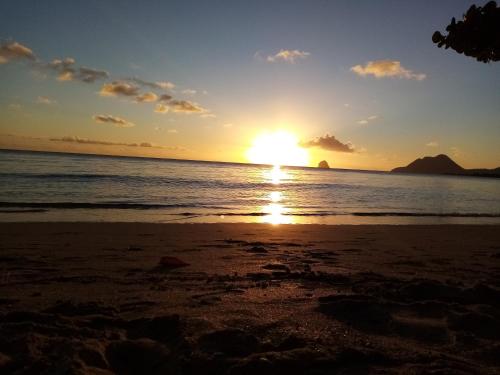 a sunset on the beach with the sun setting at Martinique hostel in Sainte-Luce