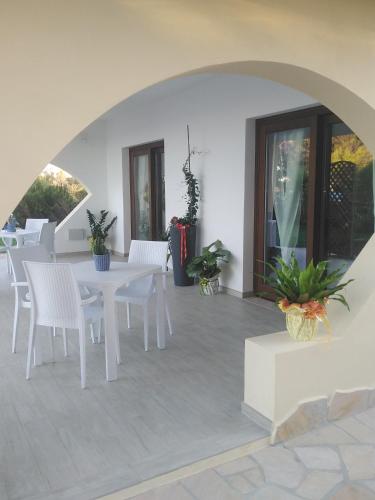 a patio with white tables and white chairs at Villa Orsola in Villaputzu