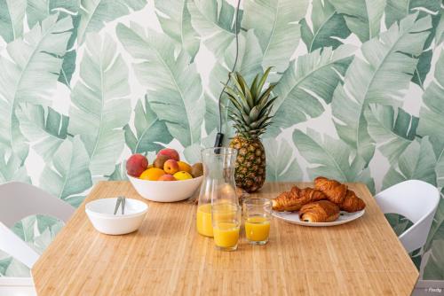 a wooden table with breakfast foods and orange juice at Fontaines de Valence d'Agen Centre Ville Netflix Proche Parking Gratuit in Valence-dʼAgen
