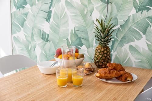 a table with a plate of food and glasses of orange juice at Fontaines de Valence d'Agen Centre Ville Netflix Proche Parking Gratuit in Valence-dʼAgen