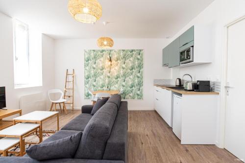 a living room with a couch and a kitchen at Fontaines de Valence d'Agen Centre Ville Netflix Proche Parking Gratuit in Valence-dʼAgen