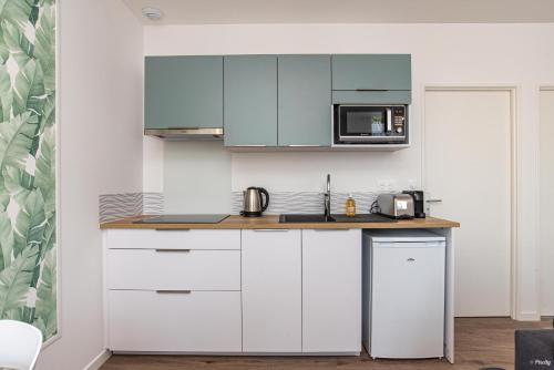 a kitchen with white cabinets and a microwave at Fontaines de Valence d'Agen Centre Ville Netflix Proche Parking Gratuit in Valence-dʼAgen