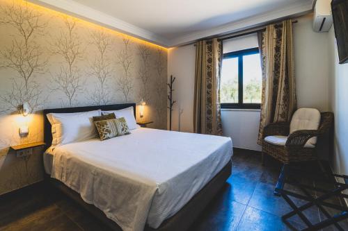 1 dormitorio con 1 cama, 1 silla y 1 ventana en Vila Fuzeta Bed & Breakfast, en Fuseta